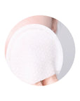 Image of a person using a cotton gauze pad to gently exfoliate their face, showing the two sides of the pad – the gauze peeling side and embossed side – in action.