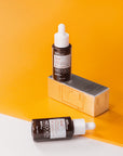 Flat lay of the serum bottle, surrounded by citrus fruits and ingredients like vitamin E and hyaluronic acid, illustrating the nourishing, antioxidant-rich formulation.