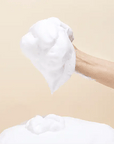Demonstrating the application of Mary & May White Collagen Cleansing Foam – Foam being massaged onto the face to remove makeup, dirt, and impurities while leaving skin soft and hydrated.