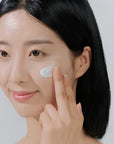 Applying Skin1004 Hyalu-Cica Water-Fit Sun Serum – Evenly applying serum to face, neck, and arms for sun protection and hydration.
